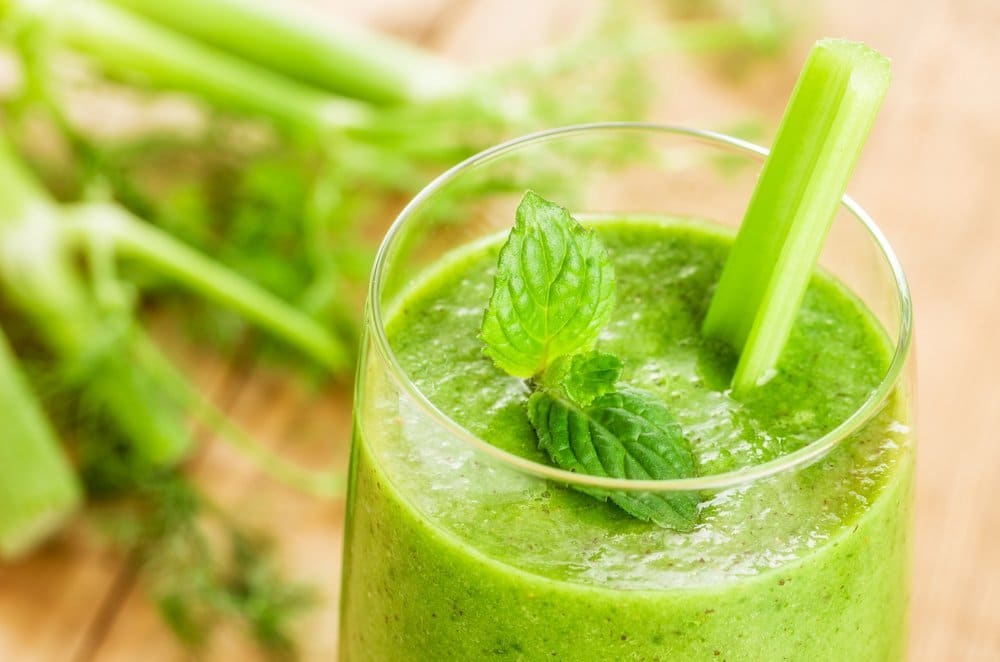Green smoothie with mint and celery on a wooden background