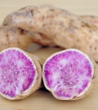 raw purple sweet potato cut in half on a wooden background